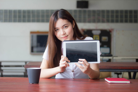 Portrait of thai adult student university uniform beautiful girl using her tablet.の写真素材