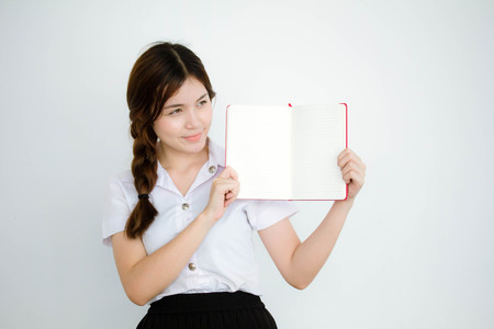 Portrait of thai adult student university uniform beautiful girl show her bookの写真素材