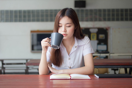 Portrait of thai adult student university uniform beautiful girl read red bookの写真素材