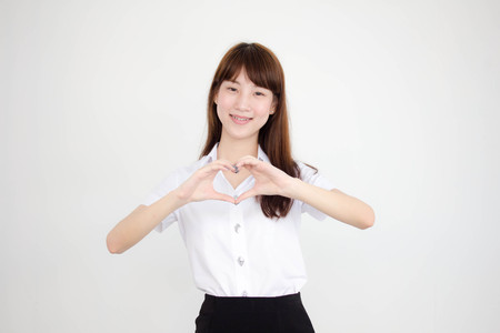 Portrait of thai adult student university uniform beautiful girl give heartの写真素材