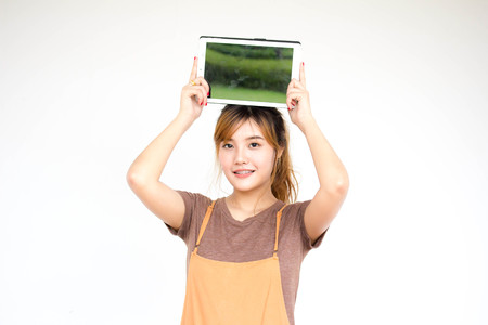 Beautiful young adult thai chinese bronze hair show her tablet.の写真素材