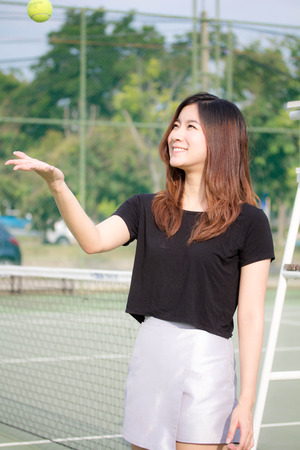 portrait of thai beautiful young adult, relaxed and smile in tennis courtの写真素材