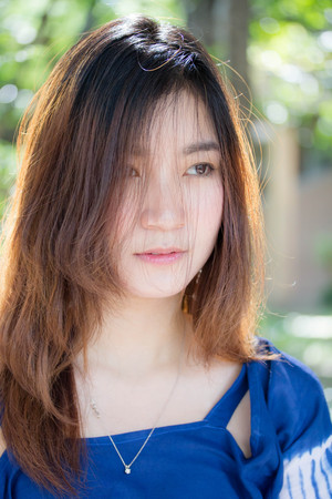 Beautiful young adult thai chinese blue tank top relax and smileの写真素材