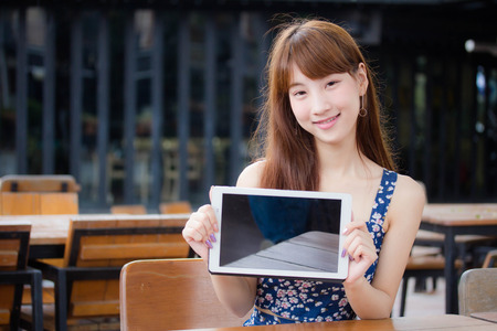 Beautiful young adult thai japanese show her tablet.の写真素材