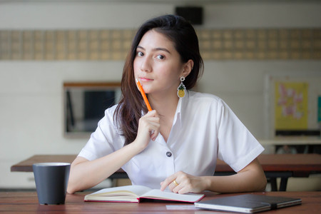 Portrait of thai adult student university uniform beautiful girl Write book