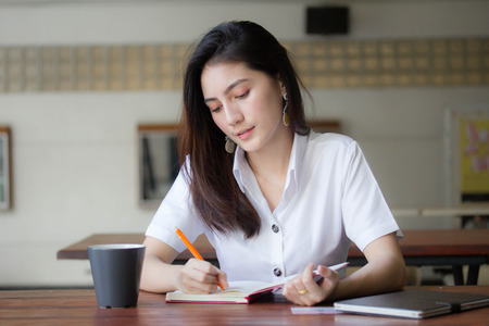 Portrait of thai adult student university uniform beautiful girl Write bookの写真素材