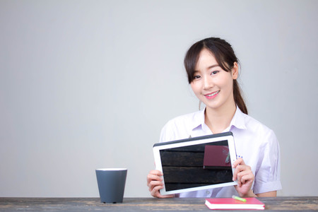 Portrait of thai high school student uniform beautiful girl using her tabletの写真素材