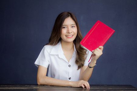 Portrait of thai adult student university uniform beautiful girl read red bookの写真素材