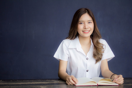 Portrait of thai adult student university uniform beautiful girl read red bookの写真素材