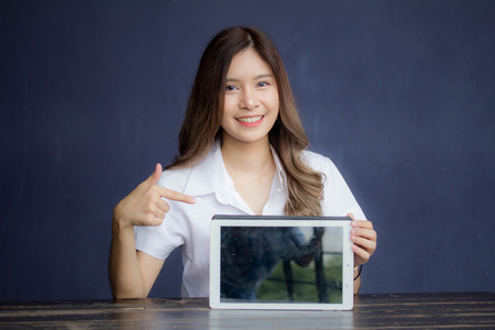 Portrait of thai adult student university uniform beautiful girl show her tablet.の写真素材