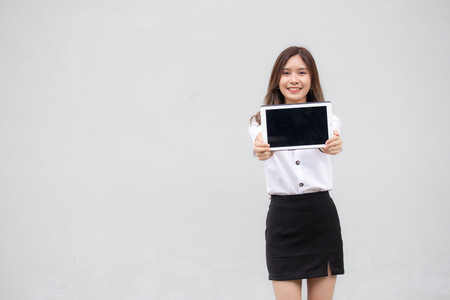 Portrait of thai adult student university uniform beautiful girl show her tablet.の写真素材