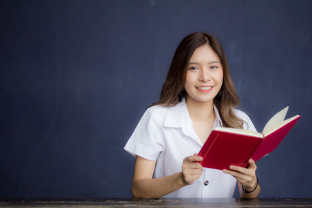 Portrait of thai adult student university uniform beautiful girl read red bookの写真素材
