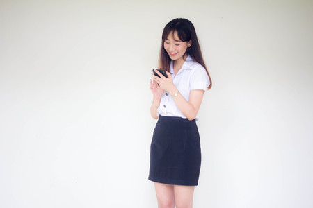 Portrait of thai adult student university uniform beautiful girl using her smart phoneの写真素材
