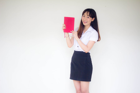 Portrait of thai adult student university uniform beautiful girl read red bookの写真素材