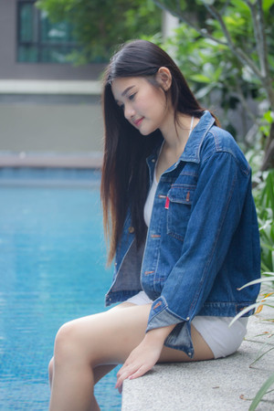 Portrait of thai adult beautiful girl blue jeans near the pool relax and smileの写真素材