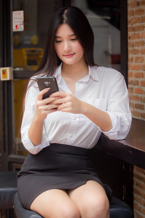 Portrait of thai adult uniform office girl calling smart phoneの写真素材