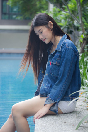 Portrait of thai adult beautiful girl blue jeans near the pool relax and smileの写真素材