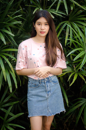 Portrait of thai adult beautiful girl pink shirt blue jeans relax and smile