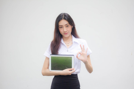 Portrait of thai adult student university uniform beautiful girl show her tablet.の写真素材