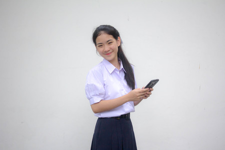 Portrait of thai high school student uniform teen beautiful girl using her phone and smileの写真素材