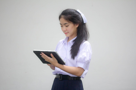 Portrait of thai high school student uniform beautiful girl using her tablet