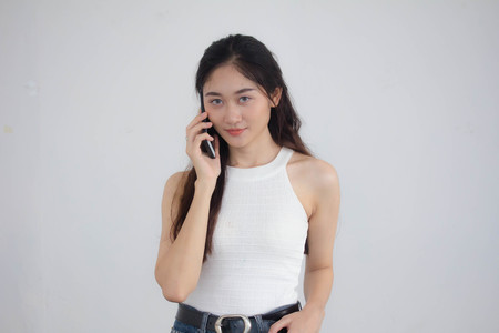 Portrait of thai china adult beautiful girl White shirt blue jeans calling smart phoneの写真素材