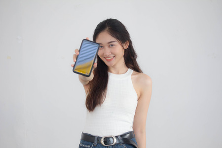 Portrait of thai china adult beautiful girl White shirt blue jeans show her smart phone