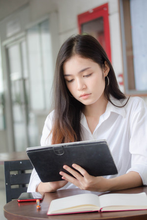 Portrait of thai adult student university uniform beautiful girl using her tablet.の写真素材