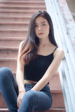 Portrait of thai china adult beautiful girl black shirt blue jeans relax and smileの写真素材