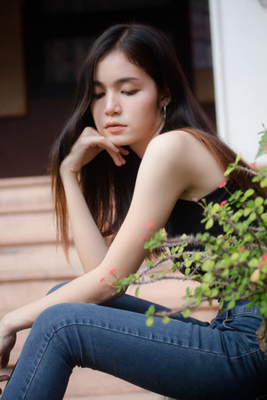 Portrait of thai china adult beautiful girl black shirt blue jeans relax and smileの写真素材