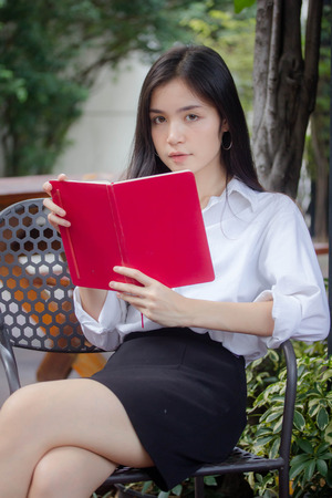 Portrait of thai adult working women white shirt reading red bookの写真素材