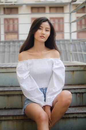 Portrait of thai adult beautiful girl White shirt blue jeans relax and smileの写真素材