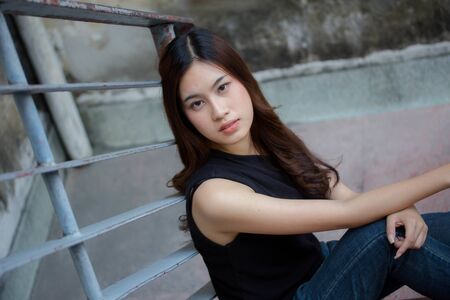 Portrait of thai china adult beautiful girl black shirt blue jeans relax and smileの写真素材