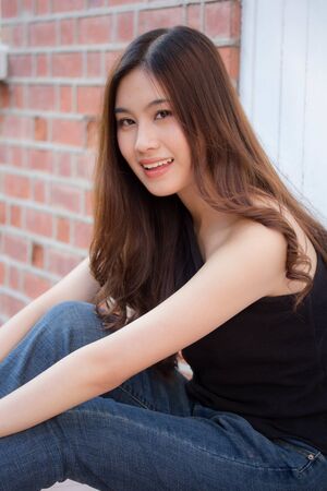 Portrait of thai china adult beautiful girl black shirt blue jeans relax and smile