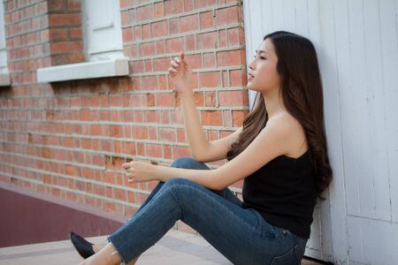 Portrait of thai china adult beautiful girl black shirt blue jeans relax and smileの写真素材