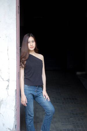 Portrait of thai china adult beautiful girl black shirt blue jeans relax and smile