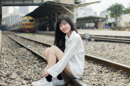 Portrait of thai japan adult beautiful girl white shirt blue jeans relax time, train station fashion