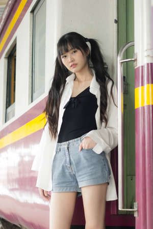 Portrait of thai japan adult beautiful girl white shirt blue jeans relax time, train station fashion
