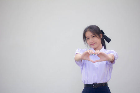 Portrait of thai high school student uniform beautiful girl give heartの写真素材