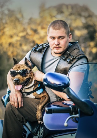Portrait of biker with fighting dog in sunglasses outdoorsの写真素材