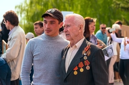 ULYANOVSK, RUSSIA - MAY 9, 2016: ULYANOVSK, RUSSIA - MAY 9, 2016: The young man is photographed with the veteran after taking part in the procession of the Immortal regiment. May, 9, 2016 in Ulyanovsk city, Russia.のeditorial素材