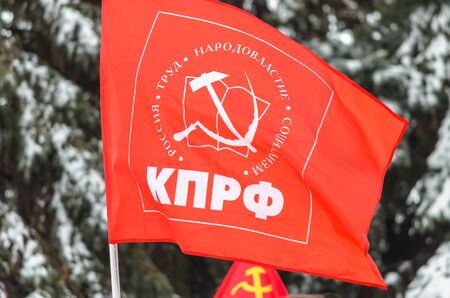 The flag of the Communist Party of the Russian Federation against the backdrop of snow-covered fir trees. The inscription on the flag "Communist Party - Communist Party of the Russian Federation"のeditorial素材