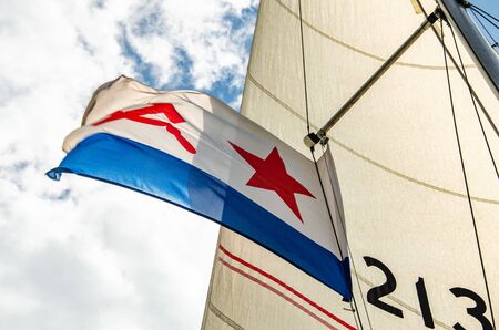 Ulyanovsk, Russia - July 27, 2019. Flag of the Russian Navy against the blue sky with clouds and a triangular sailのeditorial素材