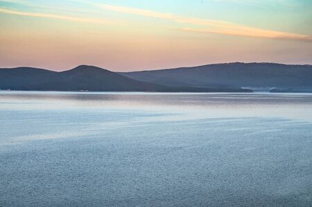 Dawn over the Ural Lake Turgoyak. Pine forest overgrown with old mountains in the background and...