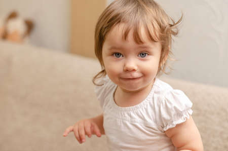 Smiling blonde wavy hair one-year-old girl close-upの写真素材
