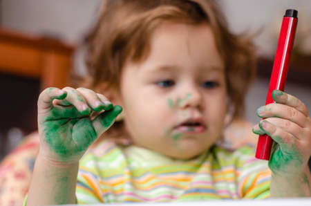 The concept of childrens creativity. Dirty baby with a marker in her handの写真素材
