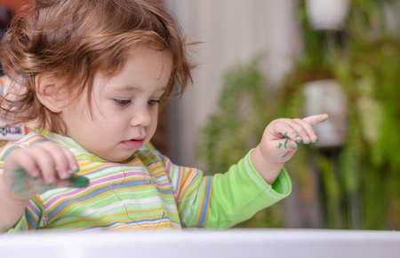 Happy one-year-old baby with a marker in her dirty handの写真素材