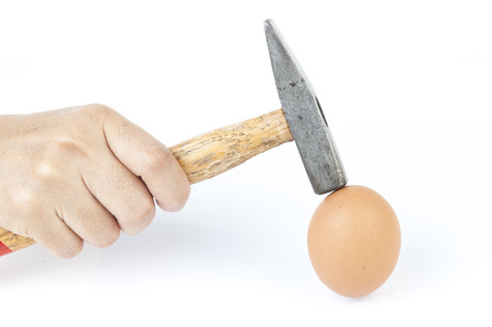 Hard egg  concept that use a hammer to knok an egg on isolated on white background close upの写真素材