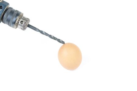 Hard egg  concept that use a drill to skrew an egg on isolated on white background close upの写真素材