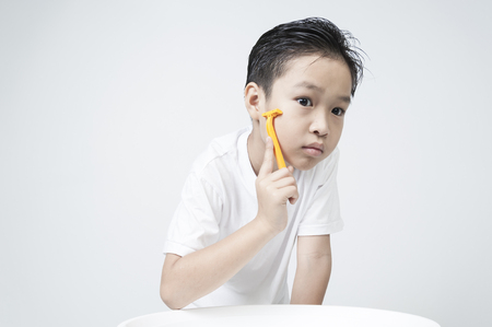 A boy try to shave by himself on white background.の写真素材